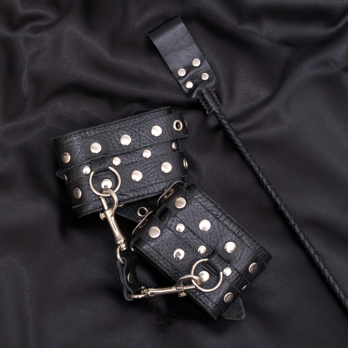 Leather handcuffs and stack on black background Leather handcuffs and stack on black background. Accessories for adult sexual game. BDSM outfit.